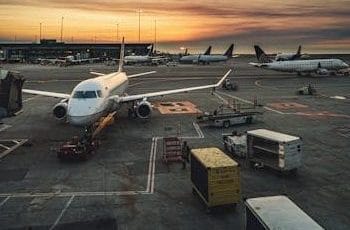 Airplanes parked at a busy airport terminal during sunset, showcasing aviation and travel.